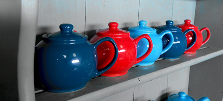 Red and blue tea pots on a dresserの写真素材