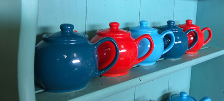Red and blue tea pots on a dresserの写真素材