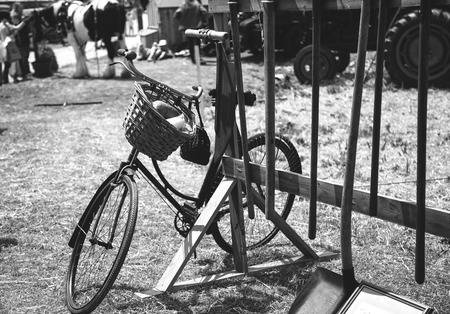 Old bike resting againt some old farming toolsの写真素材