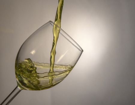 Fluid motion of coloured water in a wine glass with blownout highlightsの写真素材