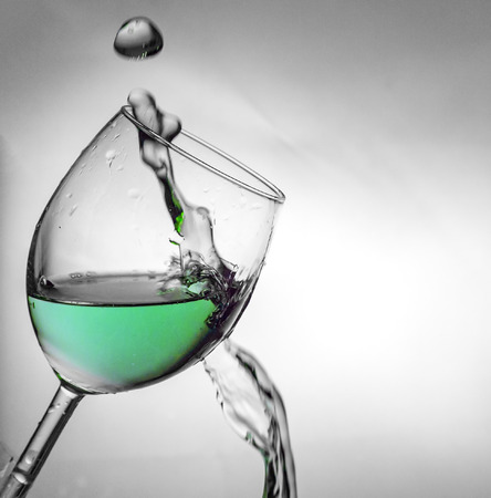 Fluid motion of coloured water in a wine glass with blownout highlightsの写真素材