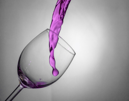 Fluid motion of coloured water in a wine glass with blownout highlightsの写真素材
