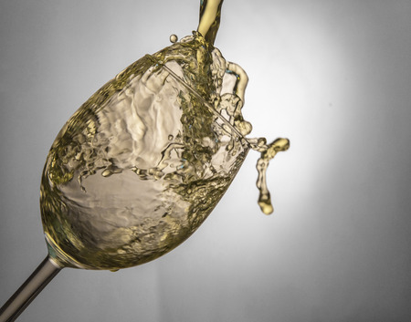 Fluid motion of coloured water in a wine glass with blownout highlightsの写真素材