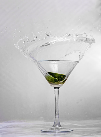 Showing a glass with a lime segment being dropped into itの写真素材