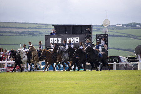 Wadebridge, Cornwall, UK, June 11 2016 - Showing horse riders, riding and doing several riding tricks with horses on green grass field at a local show.のeditorial素材