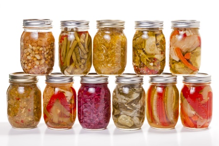 A collection of pickled and jarred vegatables in glass jars against a white background の写真素材