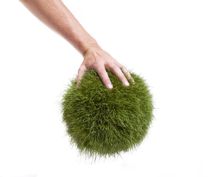 A male arm grabs a grass globe against a white background の写真素材