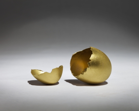 Cracked open golden egg in the spotlightの写真素材