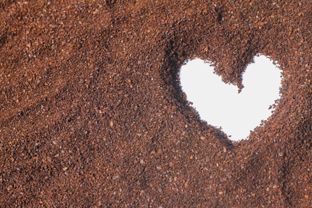 figure drawings in the shape of a heart on the cocoa powder scattered on a white backgroundの写真素材
