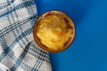 Ghee in ceramic bowl on a blue background, top viewの写真素材