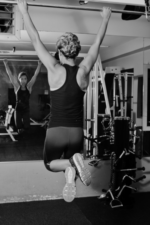 Female athlete hanging from a pull up bar.