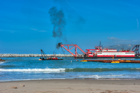 Smaller boat assisting the larger dredge barge.の写真素材