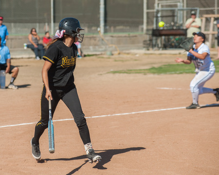 Teenager in black uniform watching her ball get caught.