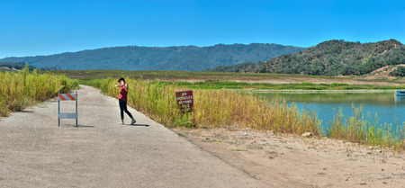 Teenage girl standing on old Highway 150 barricade at low Lake Casitas.の写真素材