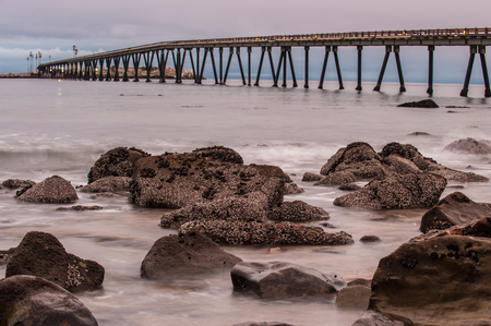 Boulders of Mussel Shoals point boulders in the breaking surf with the Richfield Pier in background.の写真素材