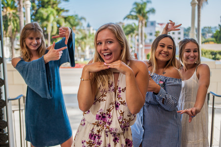 Pretty college girls together in a group making silly faces behind blond in front.の写真素材
