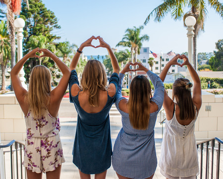 Pretty college girls together in a group holding up hands in shape of hearts from behind.の写真素材
