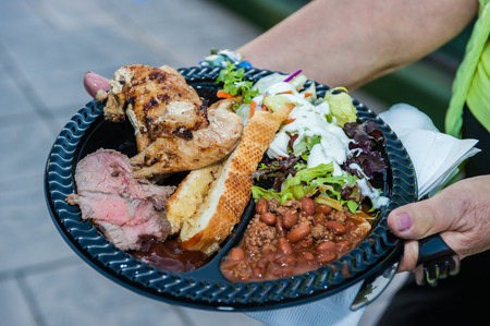 Hospitality accommodations feature a full plate of steak, chicken, salad, bread, and beans.の写真素材