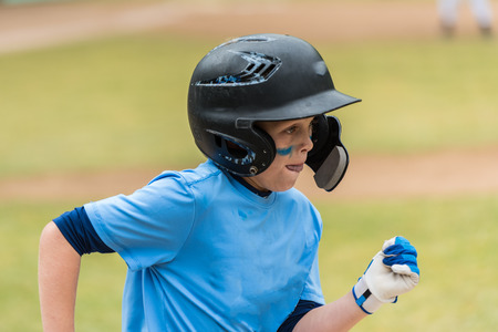 Close up of little league baseball players face showing eye black and concentration heading to first base.の写真素材