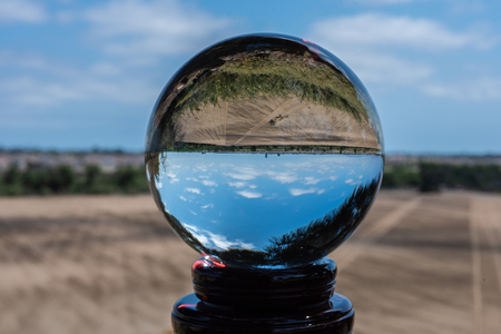Fallow farm field being worked by tractor as seen through upside down round sphere lens.の写真素材