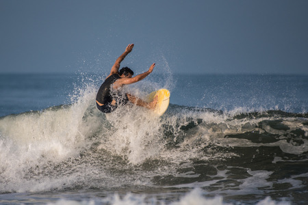 Skilled shortboarder surfer using arms as balance while splashing into the lip of the wave at...