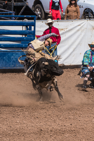 Cowboy shows expression of determination to stay on top during the bull riding at the Ventura County Fair on August 12, 2018 in California.のeditorial素材