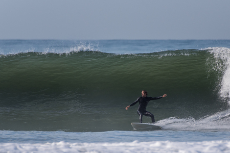 Surfer with arms spread for balance as he drops into a large wave in Ventura, California, USA during a late Autumn swell on November 28, 2018.のeditorial素材