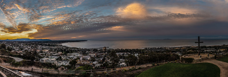 Tropical clouds glowing over the city lights of Ventura along the Pacific Ocean coast as dawn begins to light the cloudy sky.の写真素材