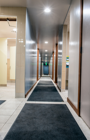 Shiny and clean hallway in mens locker room illuminated with bright LED lights along carpeted...