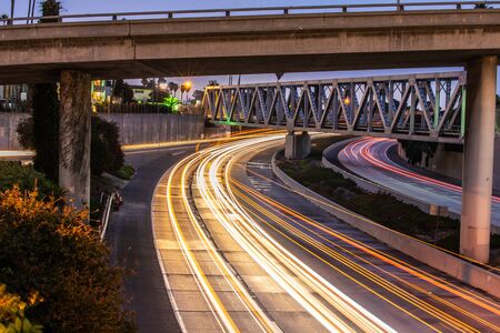 Streaking headlights and tail lights of the flowing traffic of the 101 freeway as it passes under bridges in Ventura.の写真素材