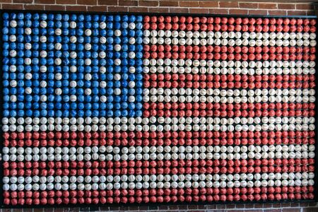 Red, white, and blue colored baseballs are arranged on wall art to form an American flag.の写真素材