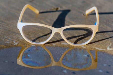 Contemporary uv protection fashion shows clear lenses reflected on wet shoreline of sunny beach.の写真素材