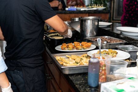 Plates of hor de vours snacks crowd the kitchen counter as chef works under pressure to prepare the...