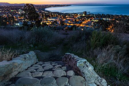 Lights of coastal city of Ventura viewed over stone cut staircase steps as dawn begins to break in the sky.の写真素材
