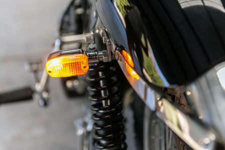 Rear lens of left turn light on vintage motorcycle shines bright as a warning to other drivers.