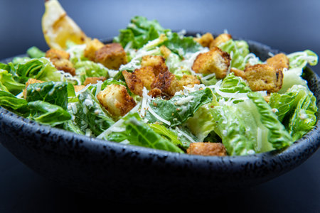 Delicious Caesar salad topped with parmesean cheese and dressing makes the mouth water and the stomach growl.の写真素材