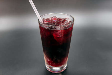 Fruity Jamaican red sweet drink flavored with sweetness and served in a clear glass with straw to quench your thirst.の写真素材