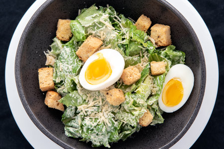 Overhead view of bowl of Caesar Salad with topped with parmesan cheese, croutons, and hard boiled egg.の写真素材
