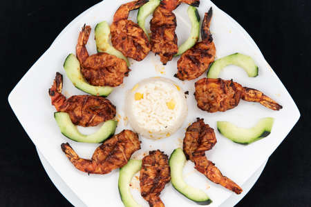 Overhead view of shrimp zarandeado arranged in perfect presentation and garnished with sliced cucumbers on a plateの写真素材