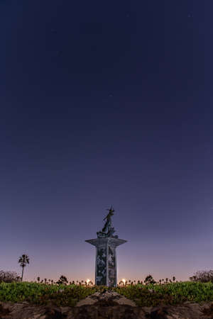 Cello playing mermaid statue stands tall under the clear night sky full of bright stars.の写真素材