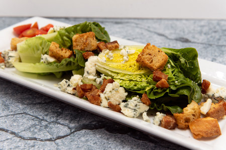 Wedge salad with fresh vegetables served on a plate topped with croutons.の写真素材