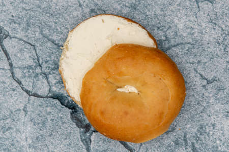 Plain toasted breakfast bagel spread thick with cream cheese and cut in two halves.