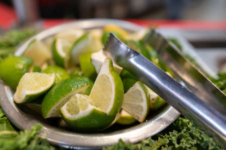 Lime slices cut into quarters and served with tongs to add to your Mexican food meal at the salsa...