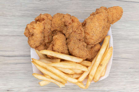 Overhead view of deep fried meal of strips of breaded chicken and a side order of french fries.
