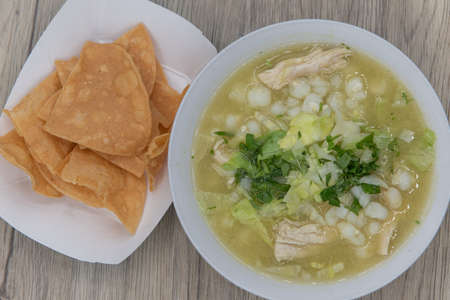 Overhead view of hearty bowl of chicken pozole soup hot from the kitchen and served with a side order of chips.の写真素材