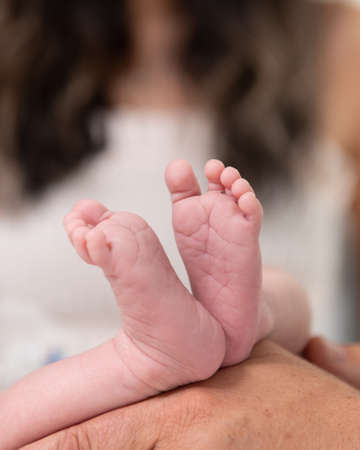 Adorable miniature feet and toes of a newborn baby with her mother and father close by.の写真素材