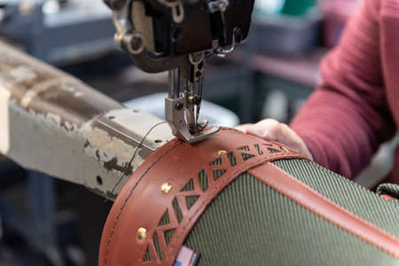 Skilled hands of factory worker guiding the embroidery sewing thread around the border of the...