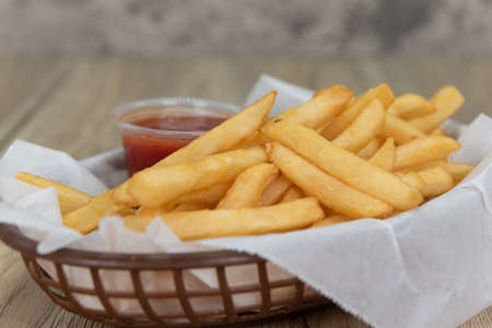 Delicious basket of french fries with ketchup for a perfect appetizer to a deep fried meal.