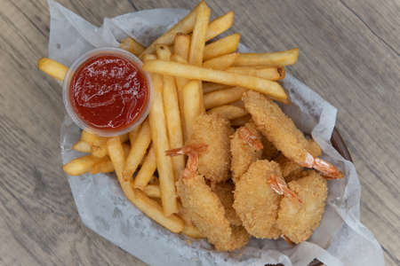 Delicious basket of fried shimp and french fries combo for a tasty seafood meal.の写真素材