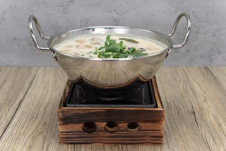 Shiny bowl of Tom Kha Kai presented in a fabulous reflective bowl on a decorative pot.の写真素材